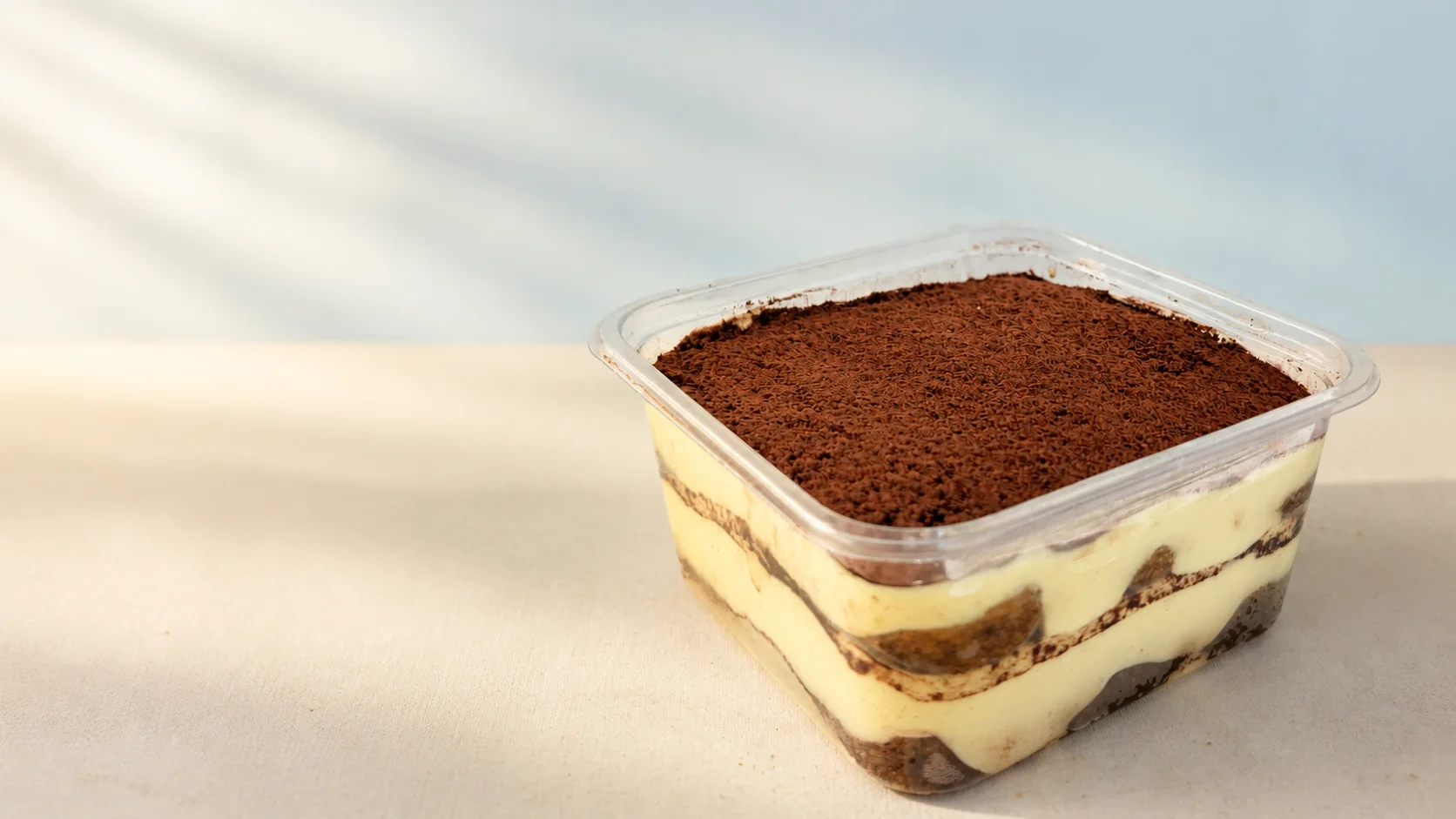 Classic Miko tiramisu with cocoa and mascarpone layers in a clear tub
