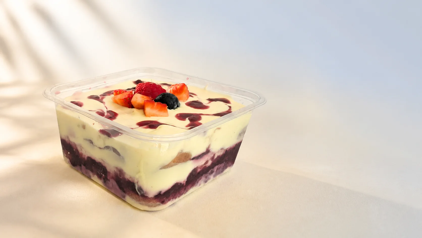 Mixed Berry Miko tiramisu with fresh berries and berry-swirled mascarpone in a clear tub